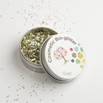 Open pot of The Glitter Tree Gold biodegradable cosmetic glitter with the lid resting on top and glitter sprinkled around the pot
