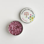 Open tin of The Glitter Tree Rose Pink biodegradable cosmetic glitter showing the sparkle texture, next to a closed tin