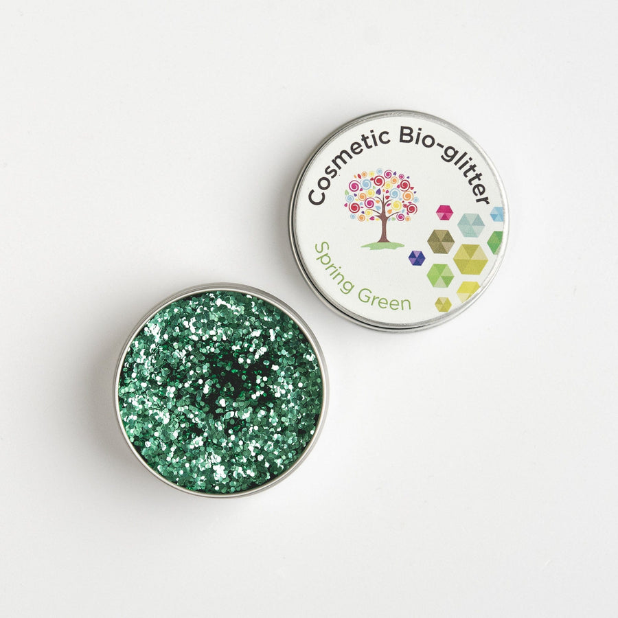 Open tin of The Glitter Tree Spring Green biodegradable cosmetic glitter showing the sparkle texture, next to a closed tin
