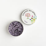 Open tin of The Glitter Tree Violet biodegradable cosmetic glitter showing the sparkle texture, next to a closed tin